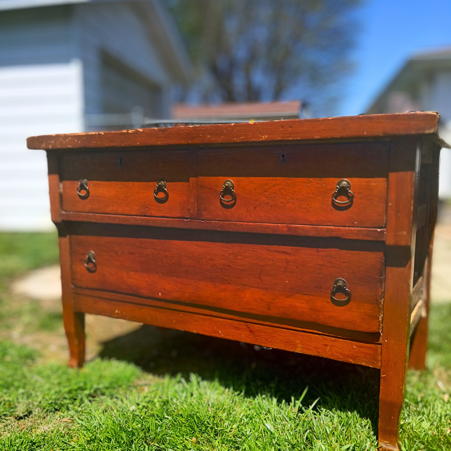 Old vintage dresser with two smaller drawers on top and one large one on the bottom sitting outside.