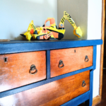 Refurbished dresser painted a navy-blue with original stained drawers. Little boy's toys sit on top.