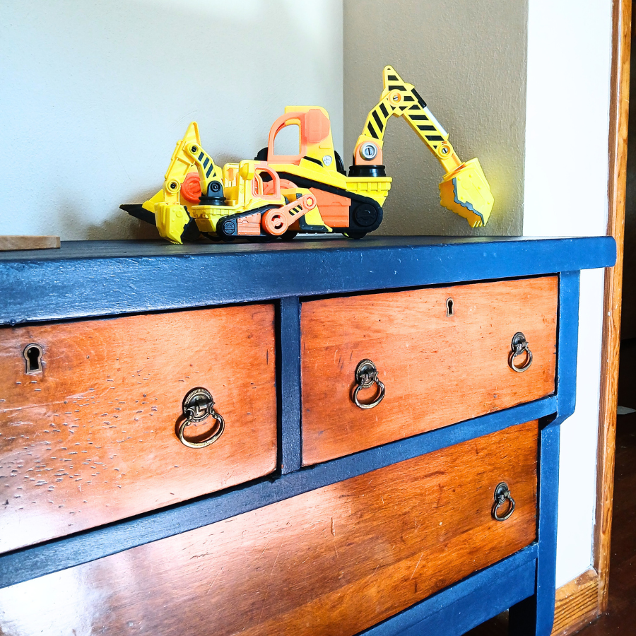 Refurbished dresser painted a navy-blue with original stained drawers. Little boy's toys sit on top. 