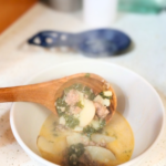 Zuppa Toscana soup in white bowl and wooden spoon.