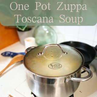 zuppa Toscana soup on stove next to wooden ladle.