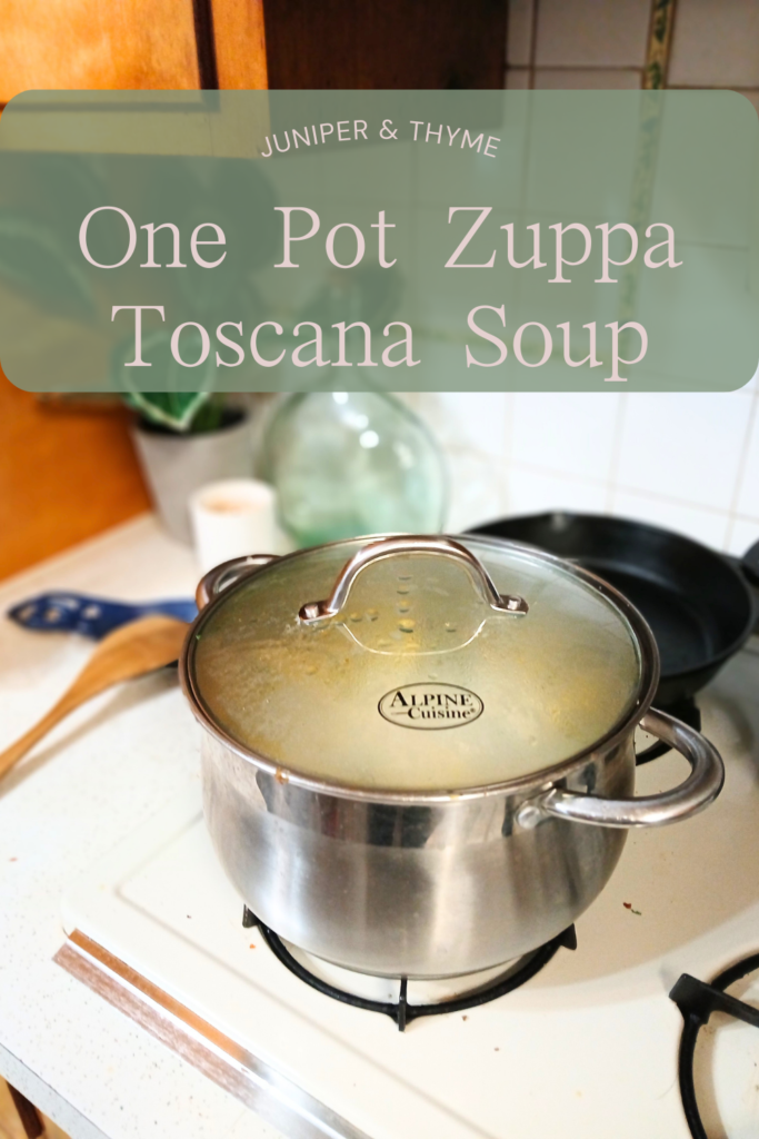 zuppa Toscana soup on stove next to wooden ladle.