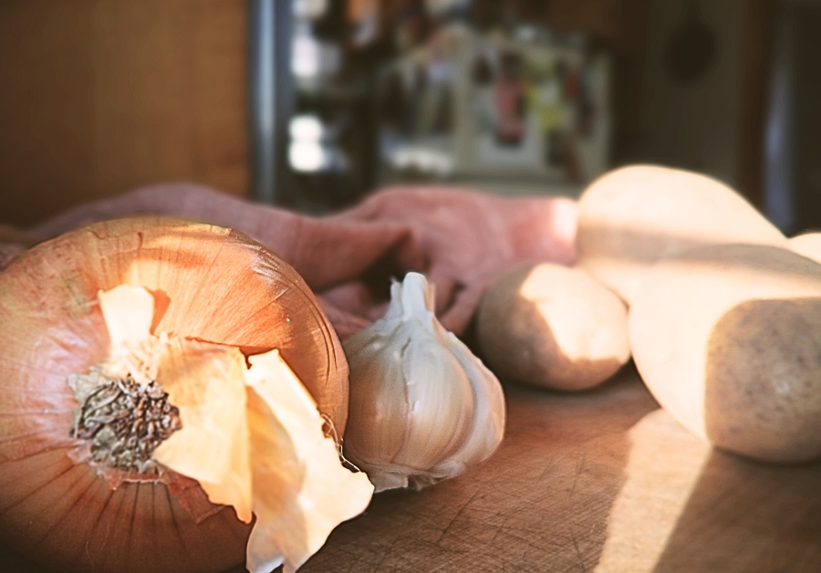 yellow onion, garlic, and potatoes on a cutting board